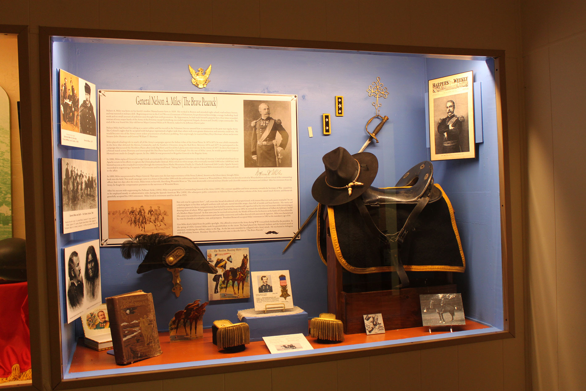 A museum exhibit in a glass enclosure with objects about General Nelson A. Miles.